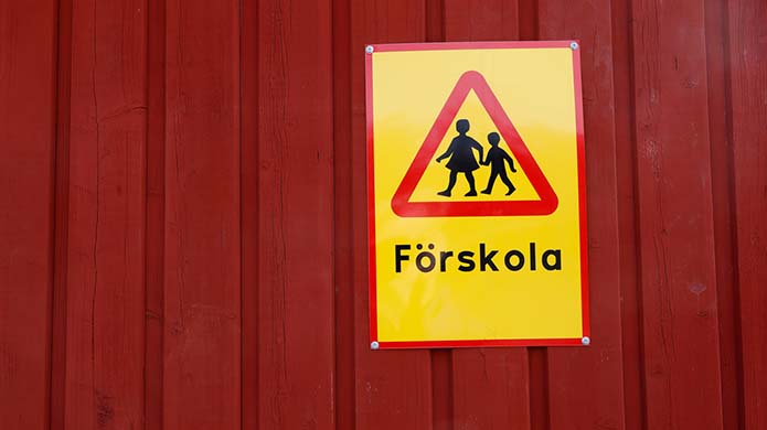 Röd husvägg, men gul varningsskylt med texten Förskola. 