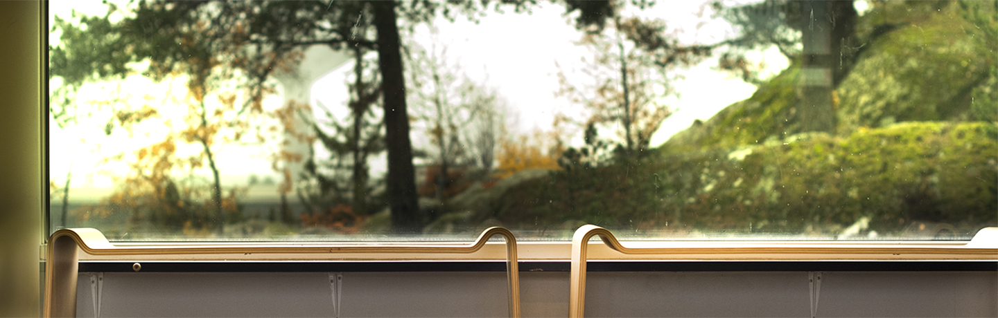 Två bänkar i trä mot fönster med natur.