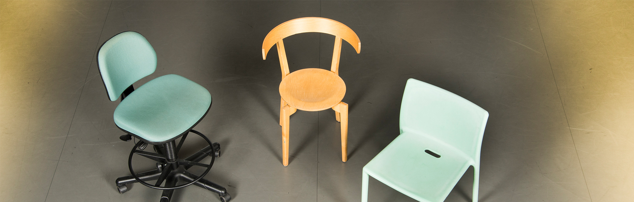 Tre olika stolar – skrivbordsstol, trästol och plaststol.