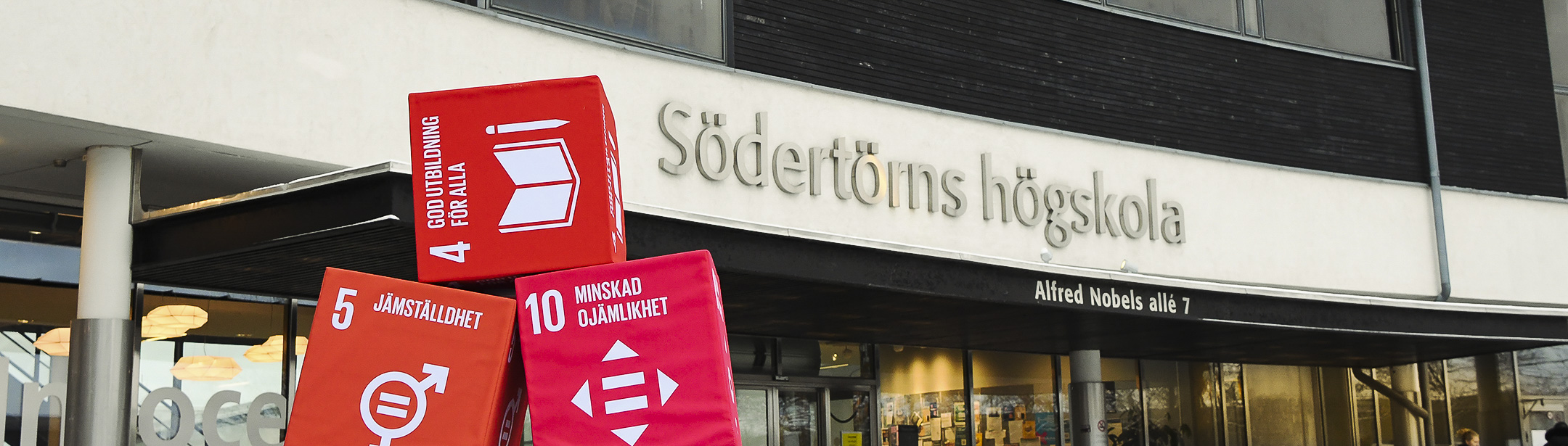 Röda boxar med FN:s Globala mål framför entrén på Södertörns högskola