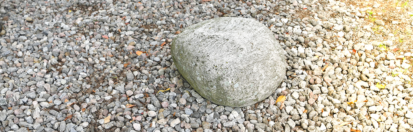 En stor sten på underlaget av grus.
