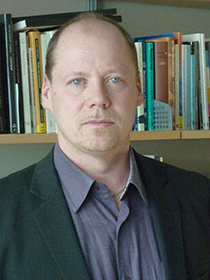 Anders Ivarsson Westerberg framför en bokhylla