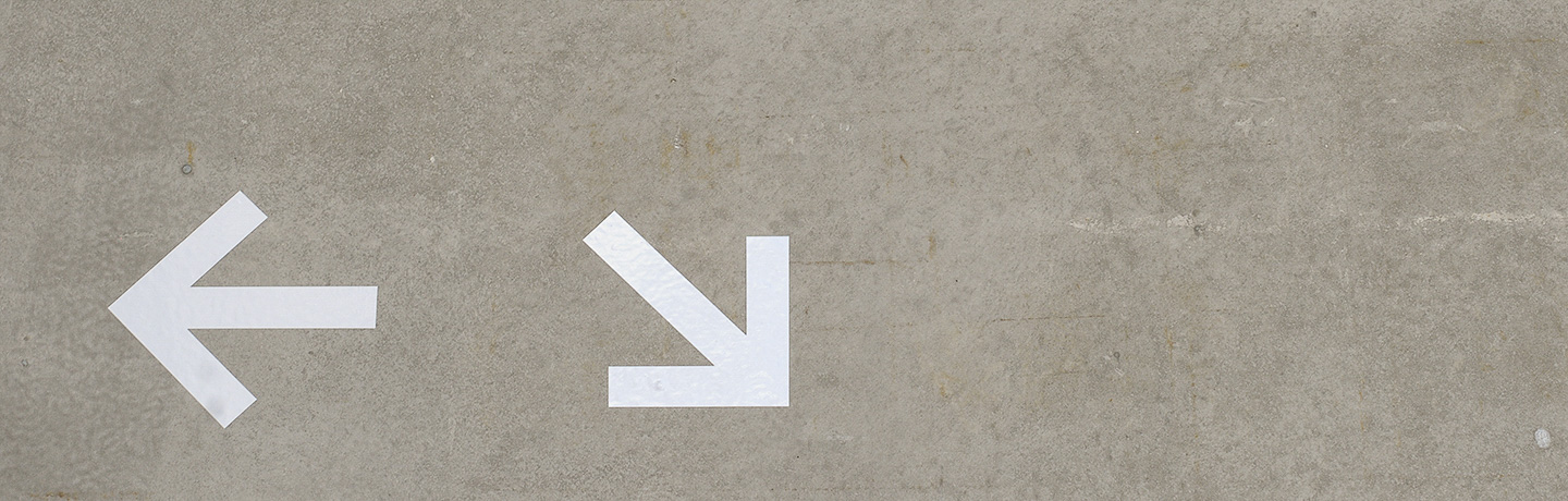 Två vita pilar på betongvägg.