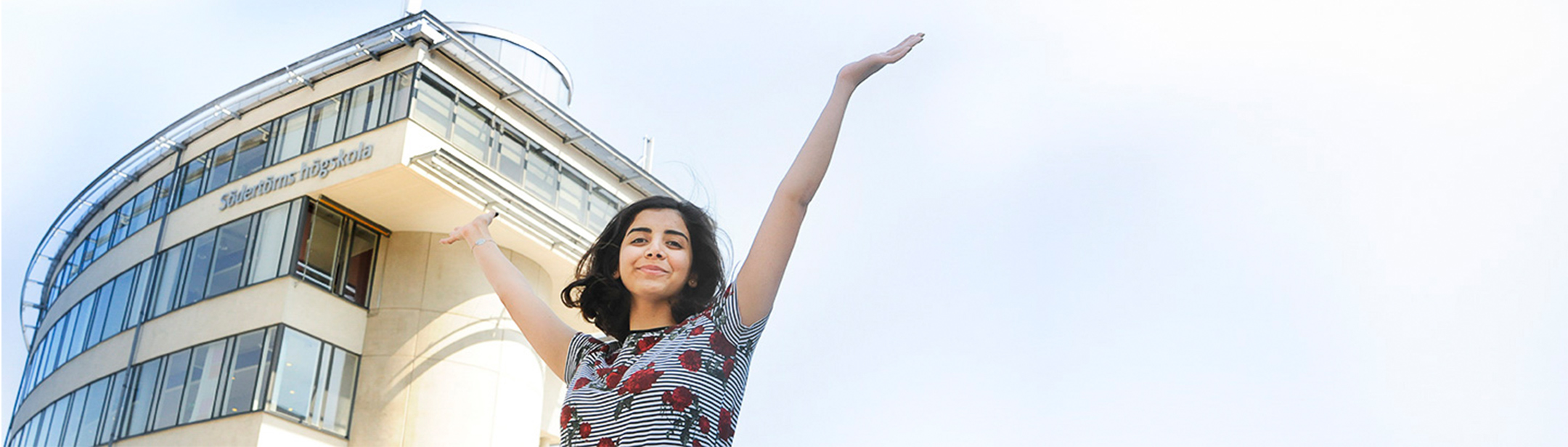 Kvinnlig student som sträcker armarna mot skyn.